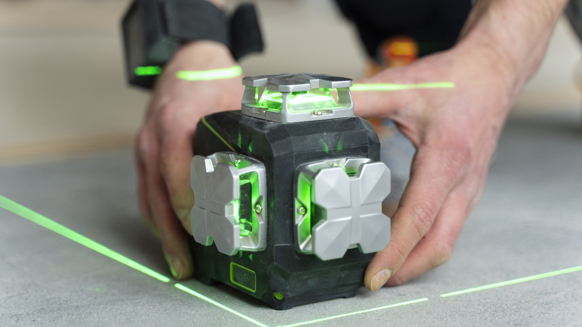un bricoleur utilise un niveau laser performant posé au sol
